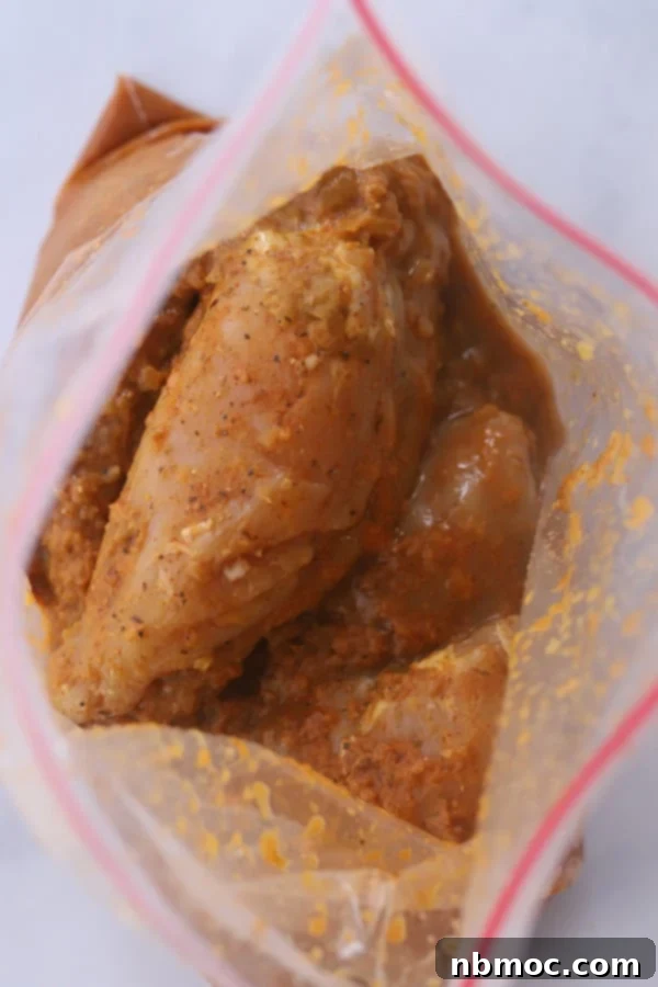 Restaurant-Style Chipotle Chicken Recipe 3 A resealable plastic bag containing marinated Chipotle chicken ingredients, with a jar of adobo sauce and other spices on the side, highlighting the marinade preparation.