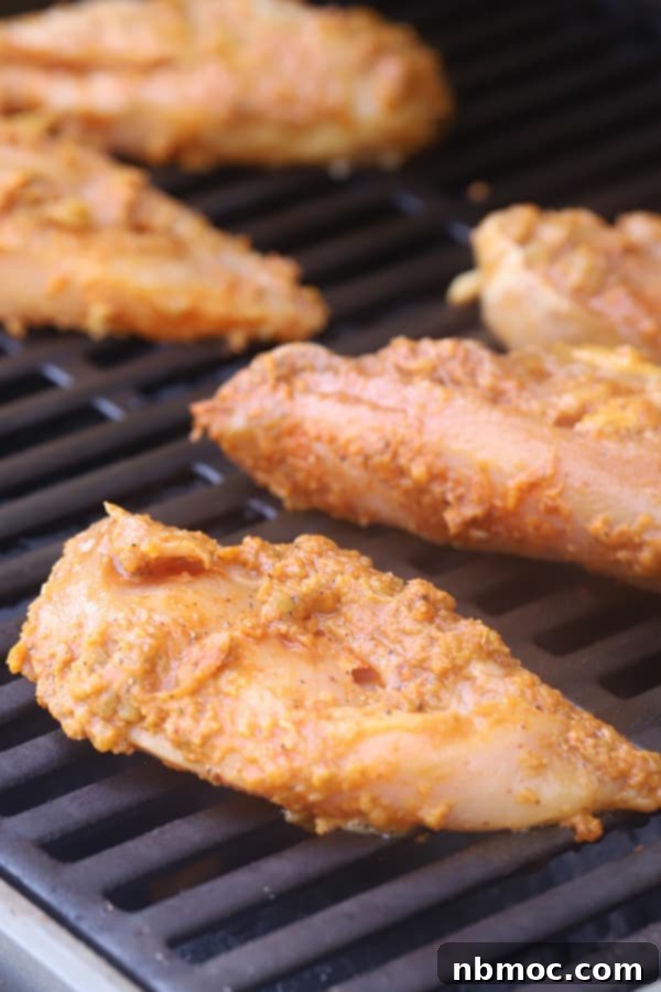 Restaurant-Style Chipotle Chicken Recipe 5 Marinated Chipotle chicken breasts sizzling on a hot grill, showing developing grill marks and char.