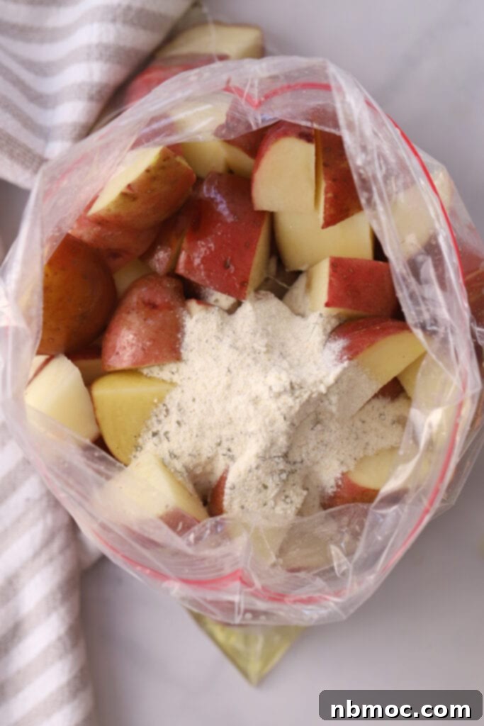 Quartered red potatoes in a ziplock bag topped with ranch seasoning mix, ready for a thorough toss.