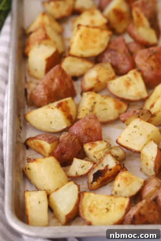 Crispy Roasted Ranch potatoes on a sheet tray, perfectly browned and ready to serve, garnished with fresh herbs.