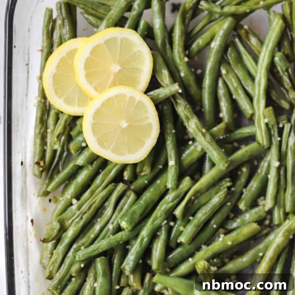 Oven roasted green beans, vibrant and perfectly seasoned, served in a white dish, an ideal easy Thanksgiving side dish.