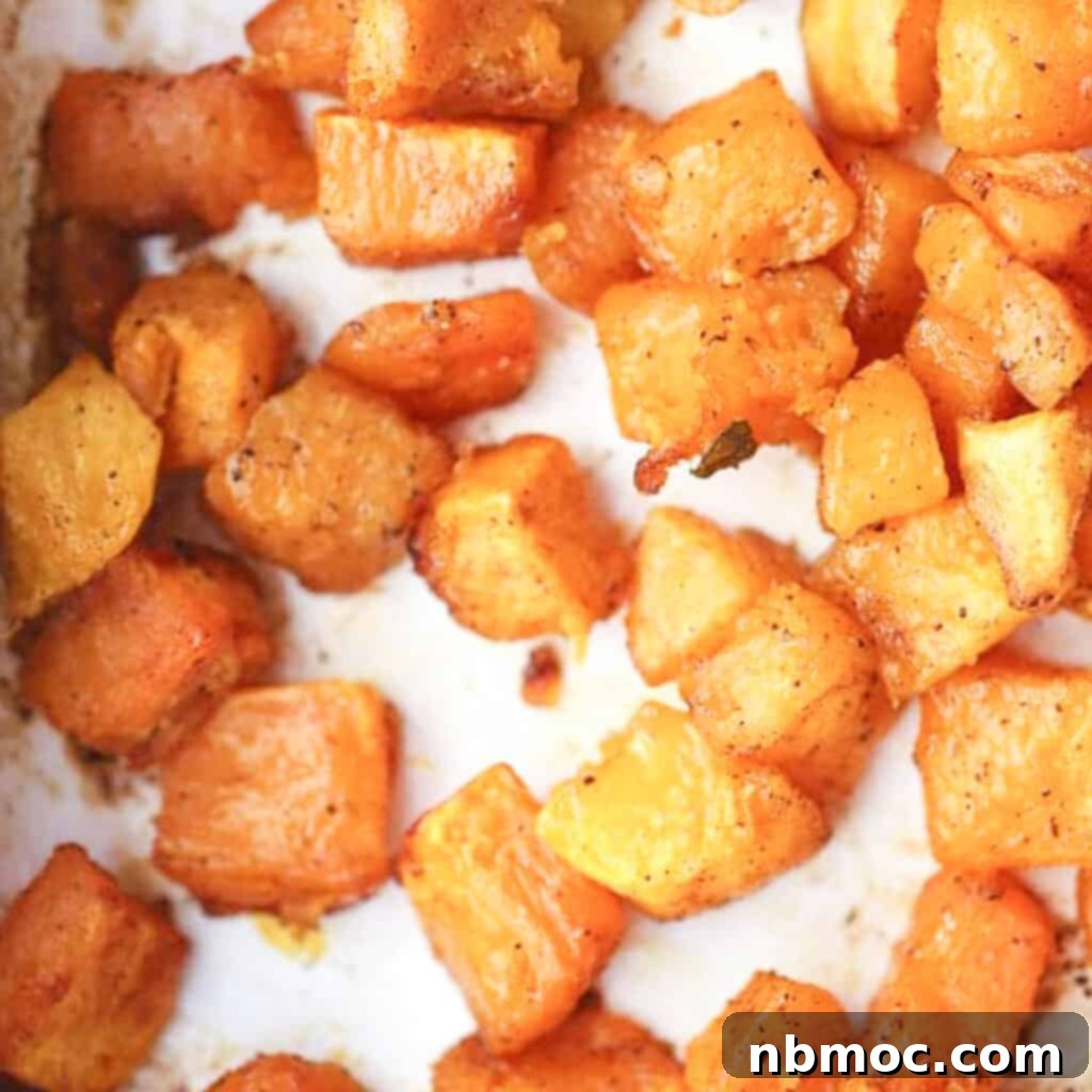 A baking dish filled with golden-brown oven-roasted squash, glistening with a cinnamon glaze, an inviting and easy Thanksgiving side dish.