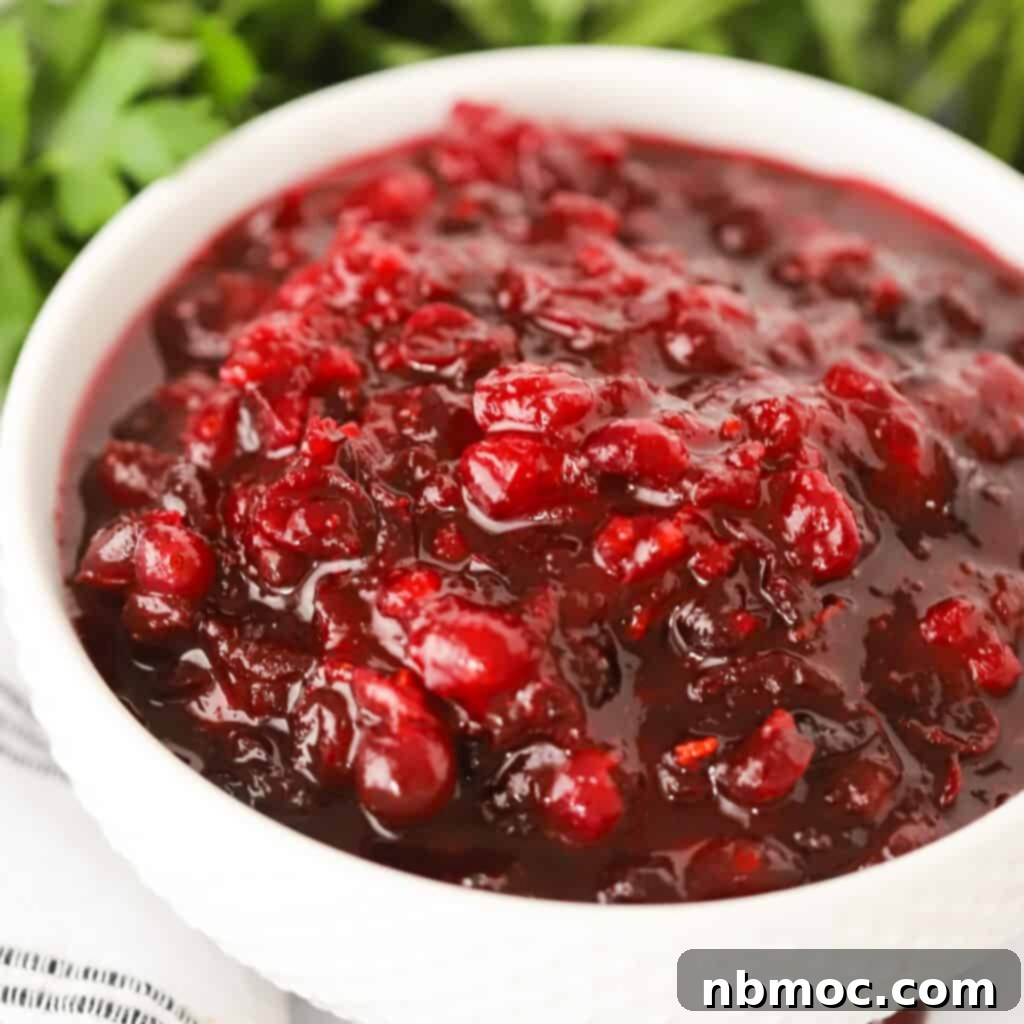 A bowl of homemade cranberry orange sauce, glistening with fresh berries and orange zest, highlighting how to make homemade cranberry sauce, a best Thanksgiving side dish.