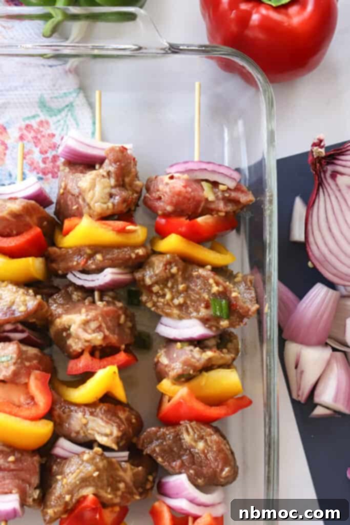 beef kabobs marinade recipe in a glass baking dish ready to cook, beef shish kabob marinade. asian skewers, asian beef marinade, marinade for beef shish kabobs. 