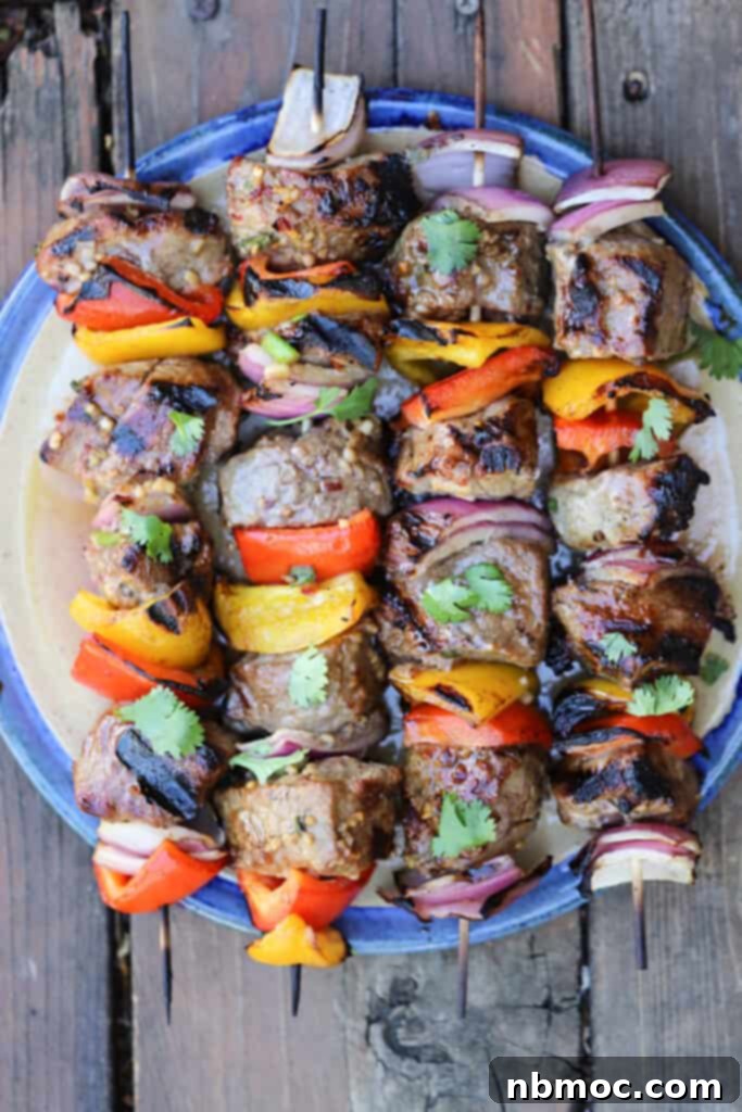 Asian Beef Steak kabobs on a blue platter, topped with fresh cilantro, beef kabob recipes, marinated shish kabobs. 