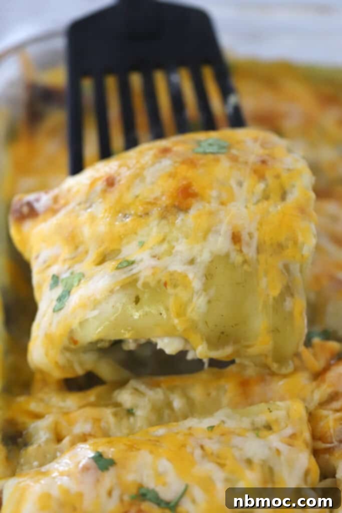 Ultimate Green Chile Chicken Enchiladas 6 A fork holding up a piece of a green chicken enchilada.