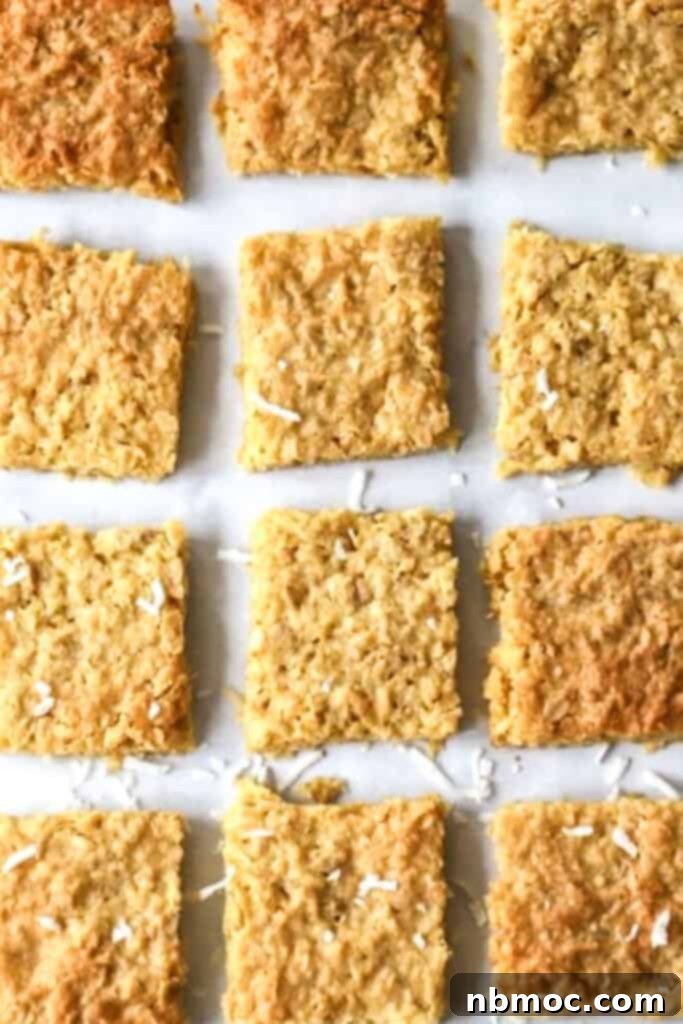 Rows of coconut cookie bars cut into squares on a baking sheet.