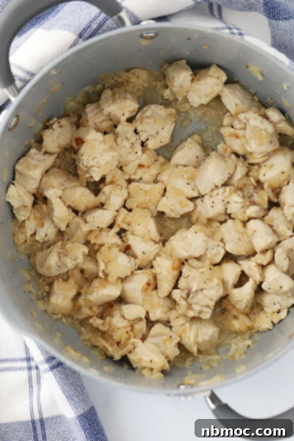 Close-up shot of cooked chicken chunks, perfectly diced and ready to be added to a hearty chili, showcasing its tender texture.