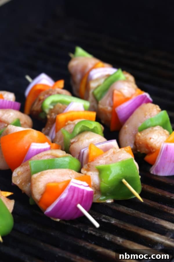 Chicken shish kabobs with peppers and onions grilling on an outdoor BBQ.