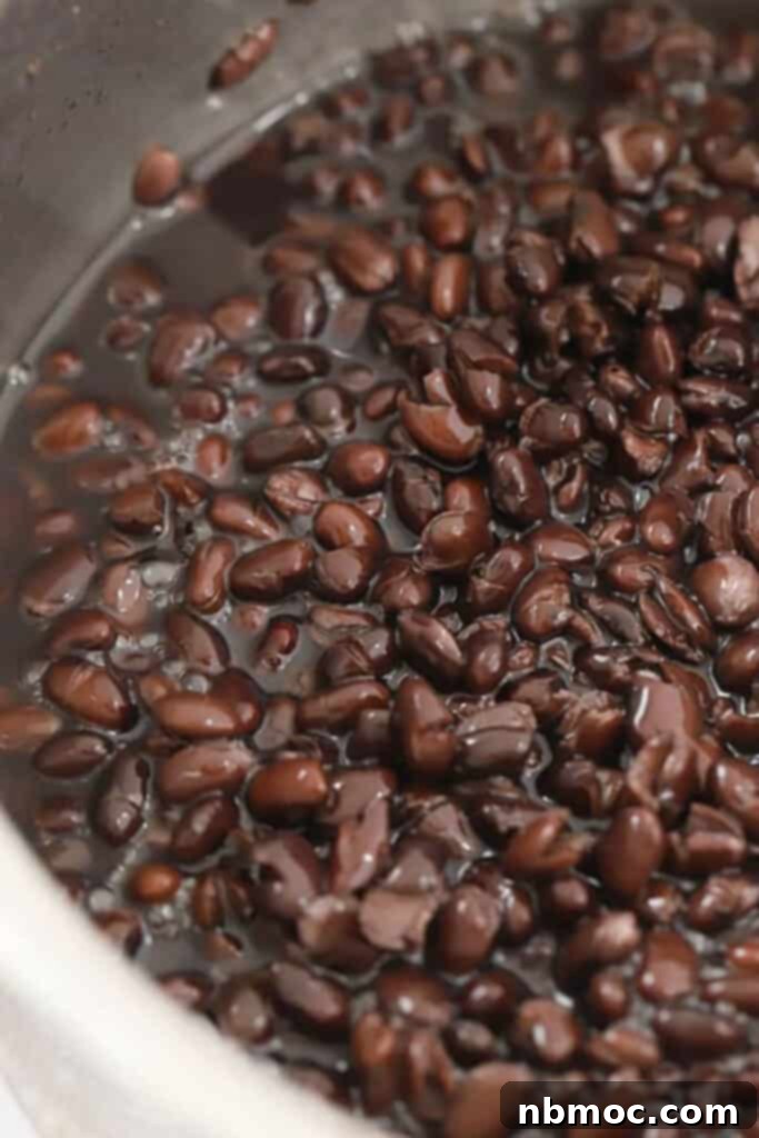 Smoky Chipotle Black Beans 6 Cooked southwest Black beans, prepared using a Chipotle copycat recipe, simmering in a large pot filled with rich, flavorful liquid.