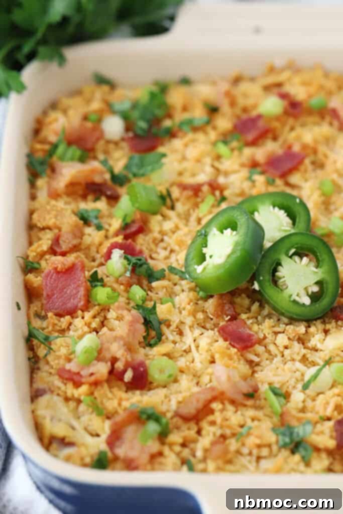 Close-up of baked jalapeno popper dip, showcasing its golden crispy cracker topping and melted cheesy interior, a perfect easy football food or party appetizer.