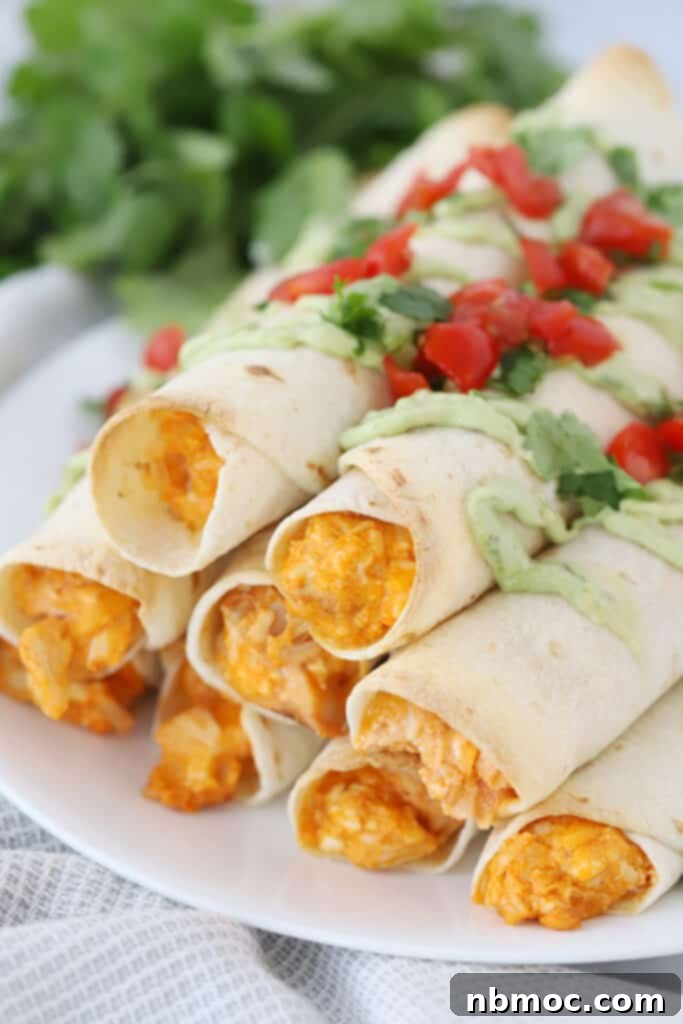 Crispy baked buffalo chicken taquitos recipe, garnished with fresh cilantro and served with a creamy dipping sauce.