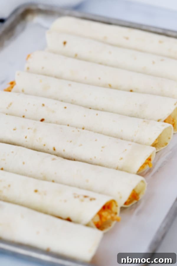 Stack of buffalo chicken taquitos with various dipping sauces on the side, highlighting buffalo cream cheese stuffed taquitos.