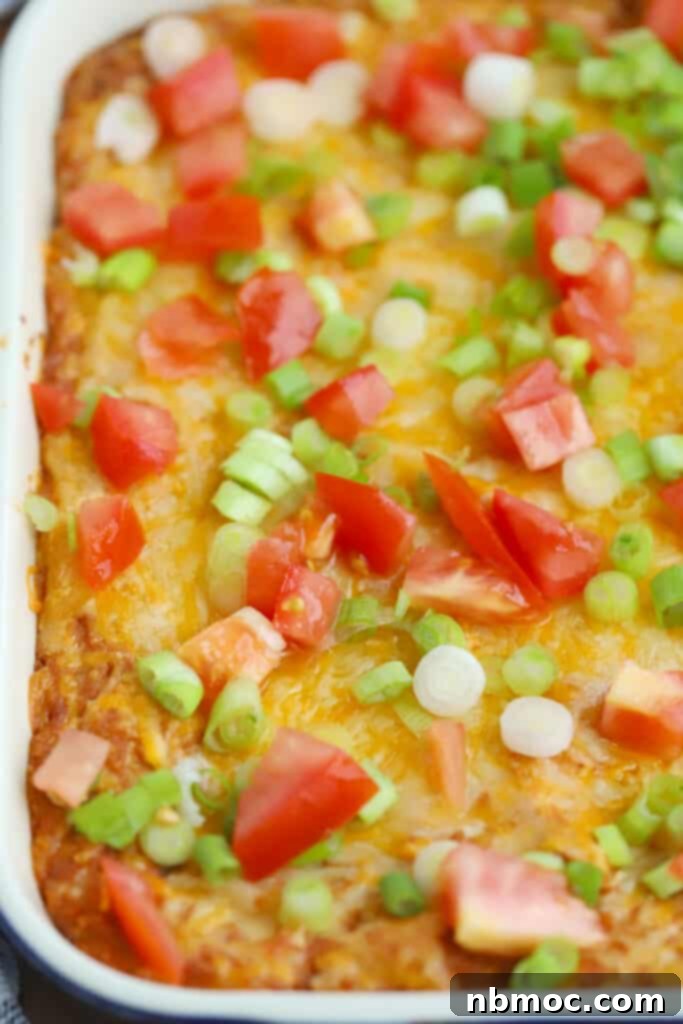 Creamy bean dip with cream cheese, garnished with fresh diced tomatoes and sliced green onions on top.