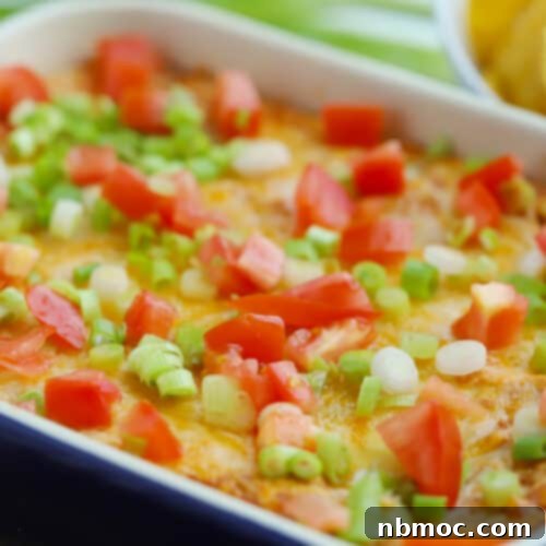 Cream cheese bean dip served with tortilla chips, garnished with fresh toppings.