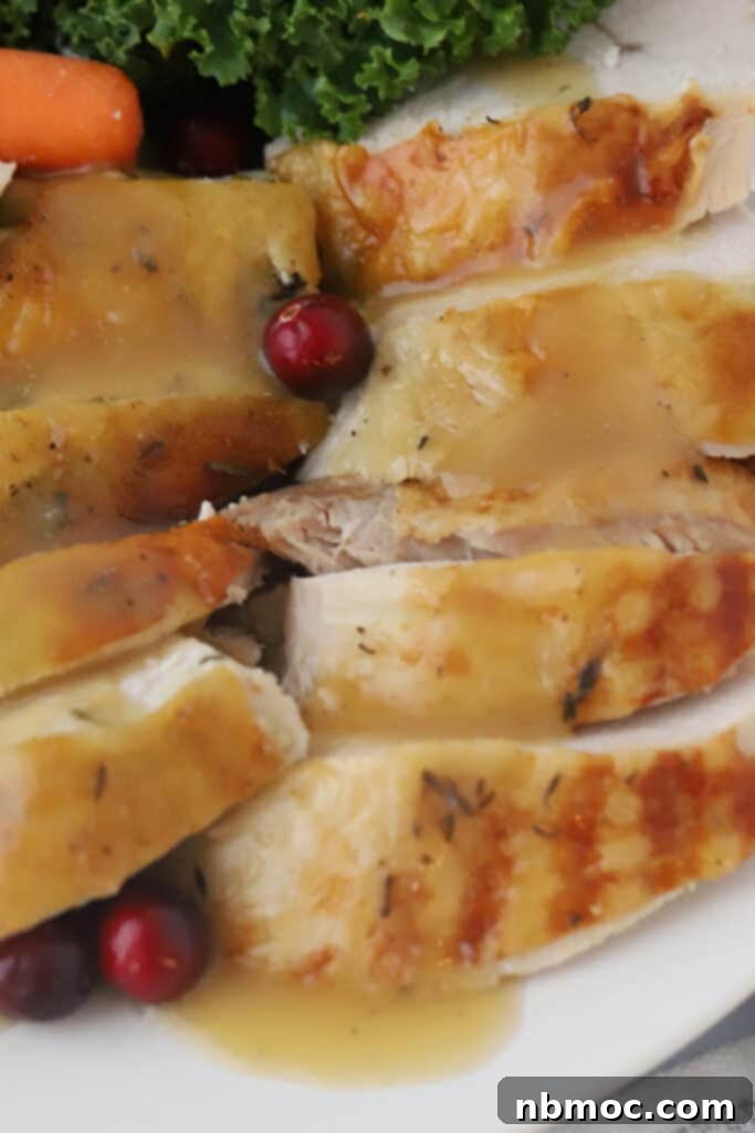 Sliced herb rubbed turkey with gravy on a plate.