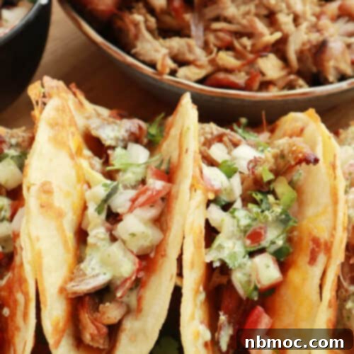 Crispy slow cooker carnitas recipe stuffed into warm taco shells, topped with fresh cilantro and onions.