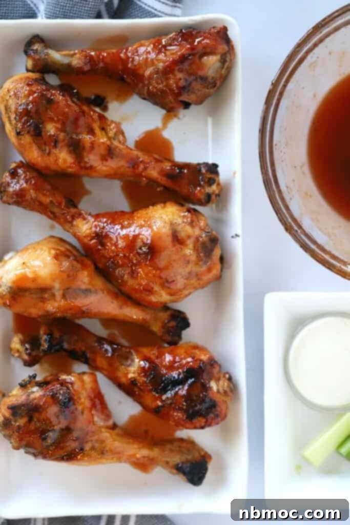 Oven baked drumsticks covered in buffalo sauce with a plate of celery sticks.