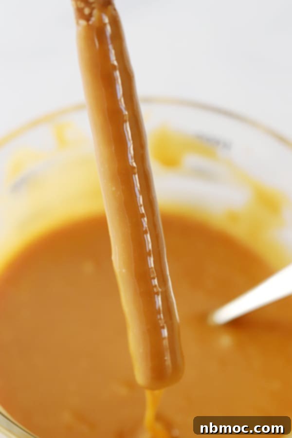 Caramel chocolate dipped pretzels, dipping into homemade caramel.