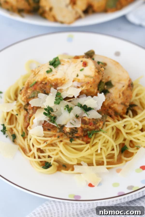 Effortless Creamy Tuscan Slow Cooker Chicken 3 A dinner plate of spaghetti topped with Tuscan Chicken Crockpot Recipe. Tuscan chicken in crock pot over pasta.