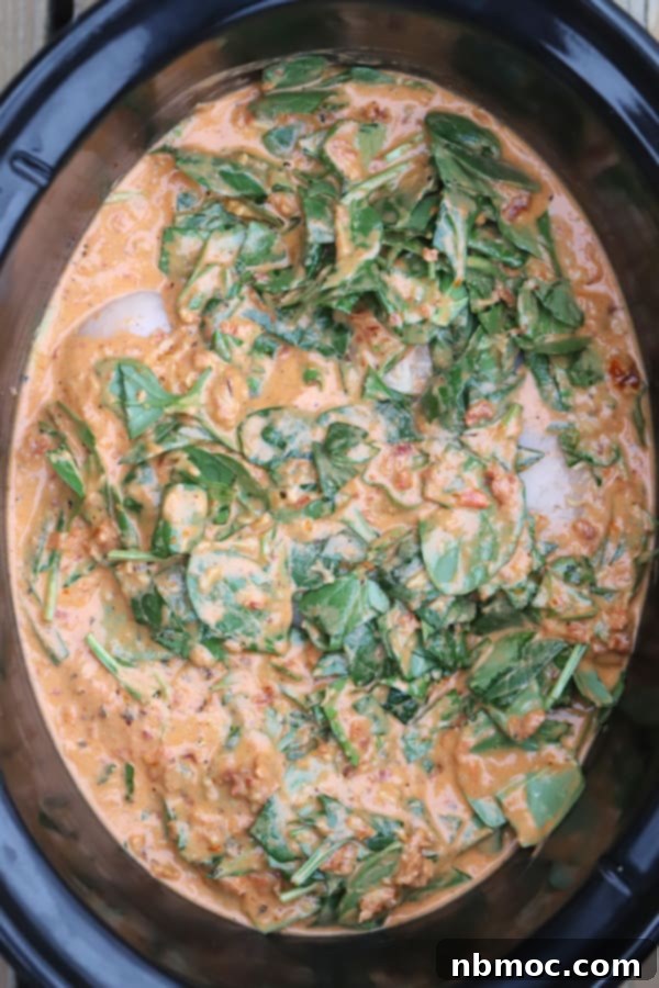 Effortless Creamy Tuscan Slow Cooker Chicken 5 Tuscan chicken crockpot full of chicken, spinach, and alfredo sauce; an easy chicken slow cooker dinner idea. tuscan chicken in slow cooker. tuscan chicken crockpot.