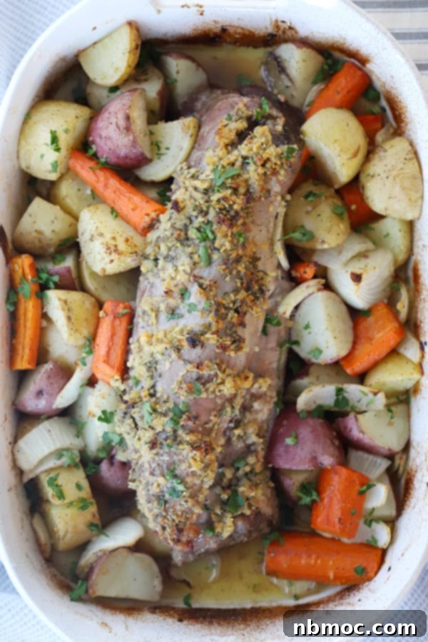Garlic Herb Pork Tenderloin with Roasted Potatoes 3 pork tenderloin roasted with with potatoes and carrots in a large baking dish.