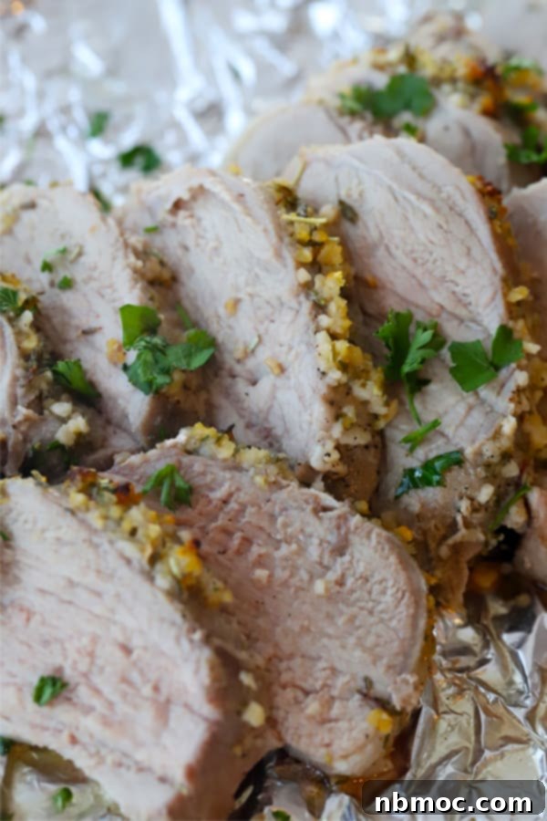 Garlic Herb Pork Tenderloin with Roasted Potatoes 4 pork tenderloin sliced on a plate with fresh herbs, a delicious pork tenderloin with potatoes.