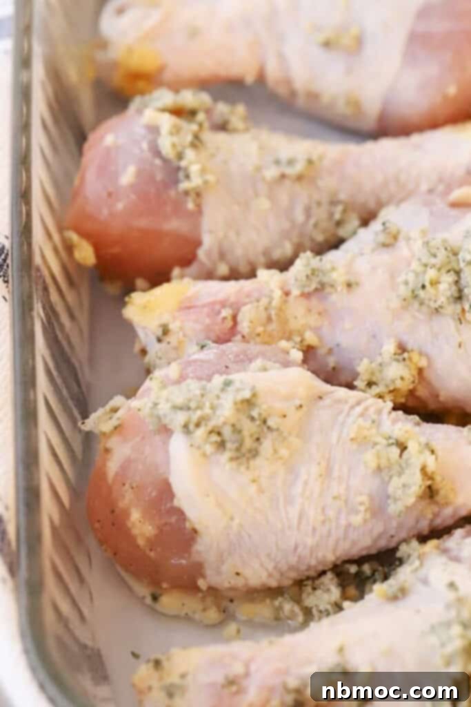 Golden Garlic Butter Drumsticks 2 A baking dish full of raw chicken drumsticks covered in garlic butter ready to bake.