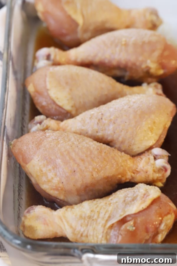 Raw honey soy chicken drumsticks marinating in a baking dish, prepared for oven baking.