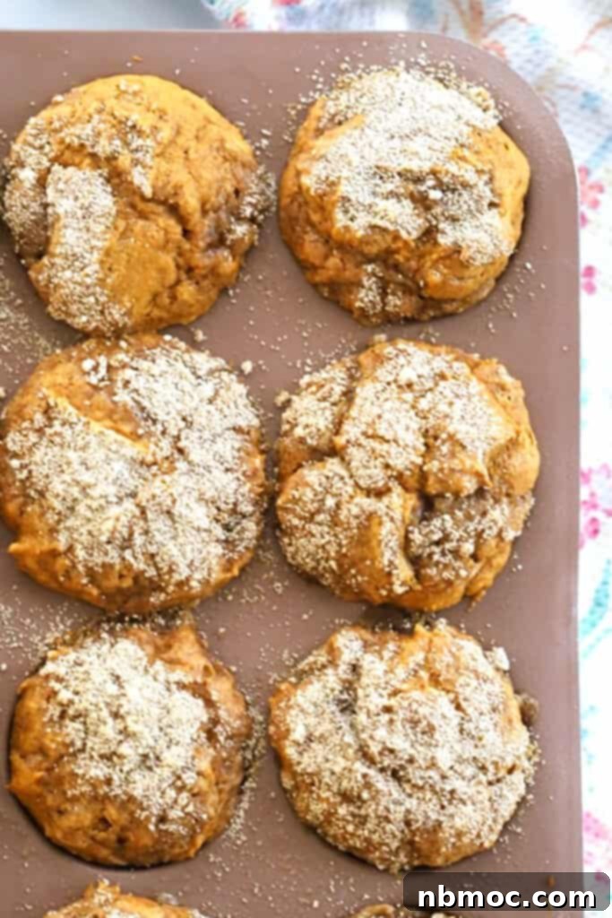 Einkorn Pumpkin Muffins with crumble topping cooling in a muffin pan.