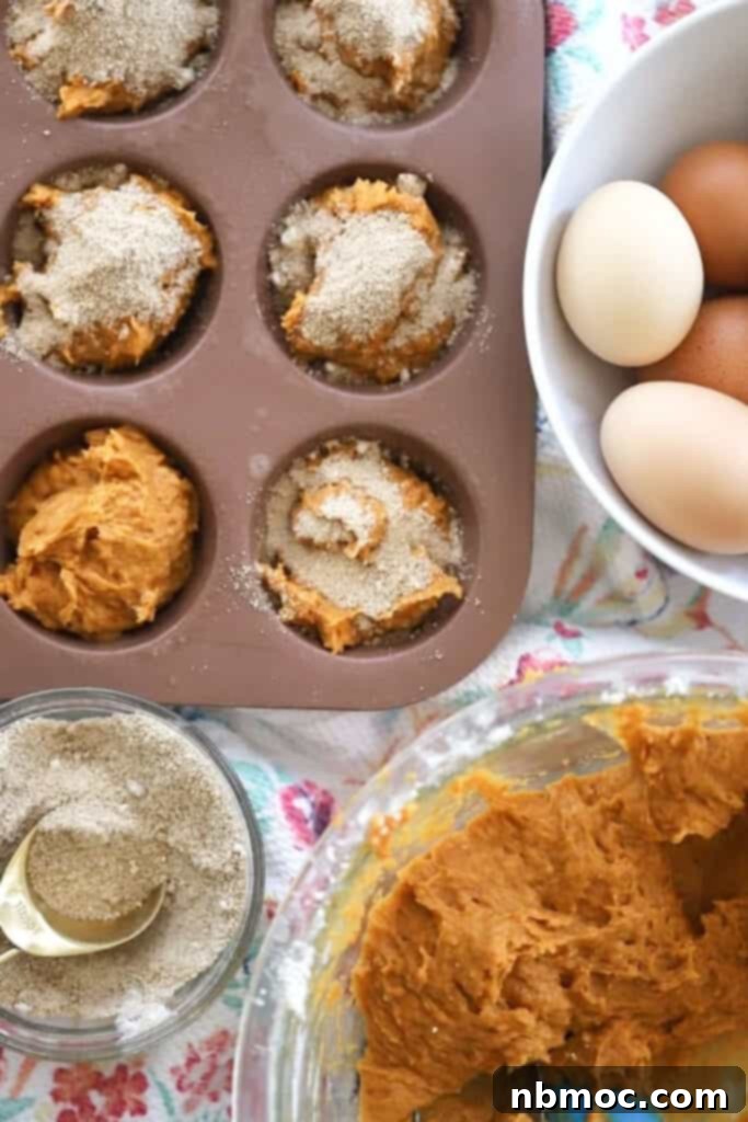 A bowl of pumpkin muffin batter with a muffin tin filled and ready to bake.
