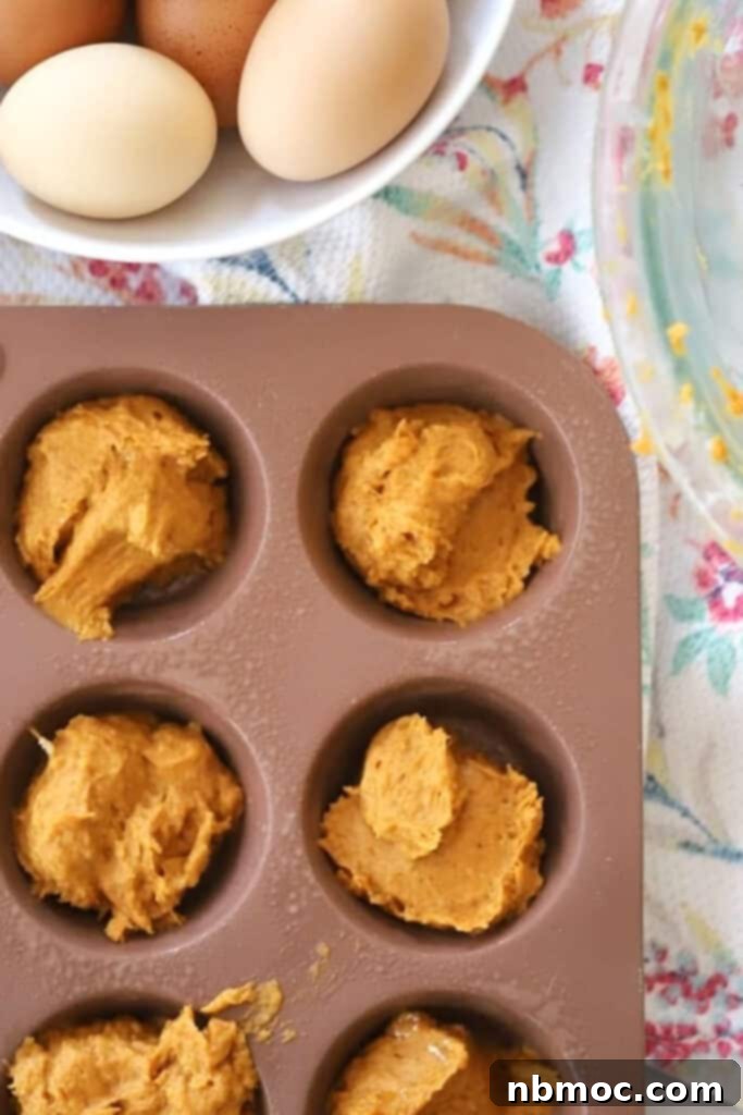 Pumpkin muffin batter inside a muffin tin ready to bake.