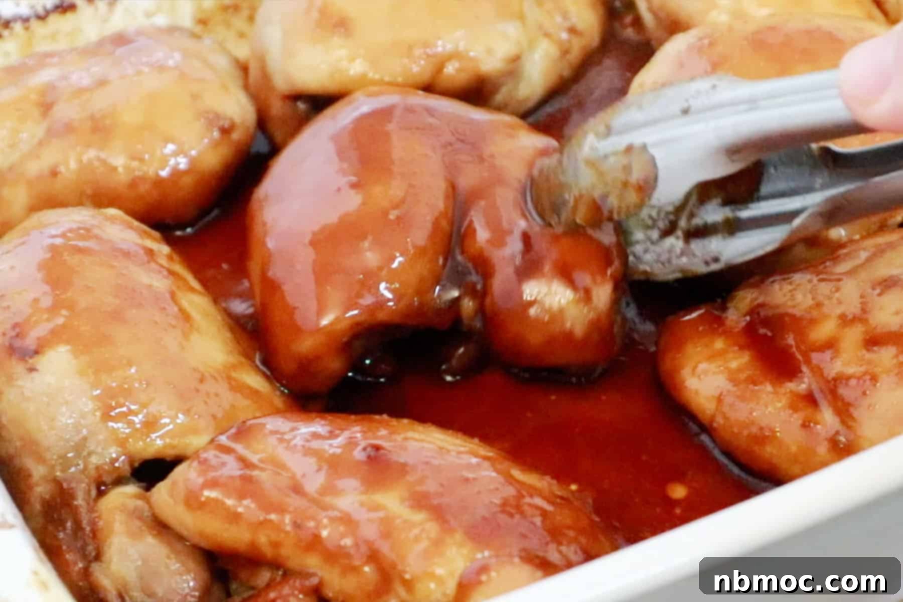 Honey Soy Chicken Thighs being turned over mid bake, soy chicken thighs. soy glaze chicken. Soy sauce honey chicken. 