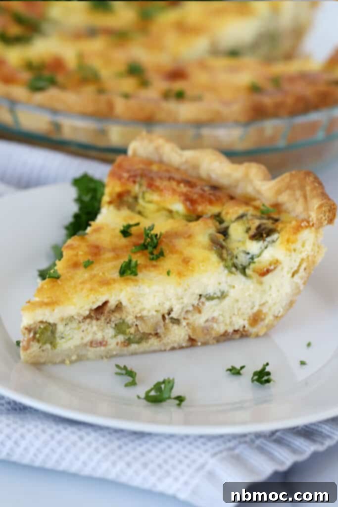 A slice of bacon asparagus quiche on a plate, showcasing the perfectly baked crust and colorful filling, ready to eat.