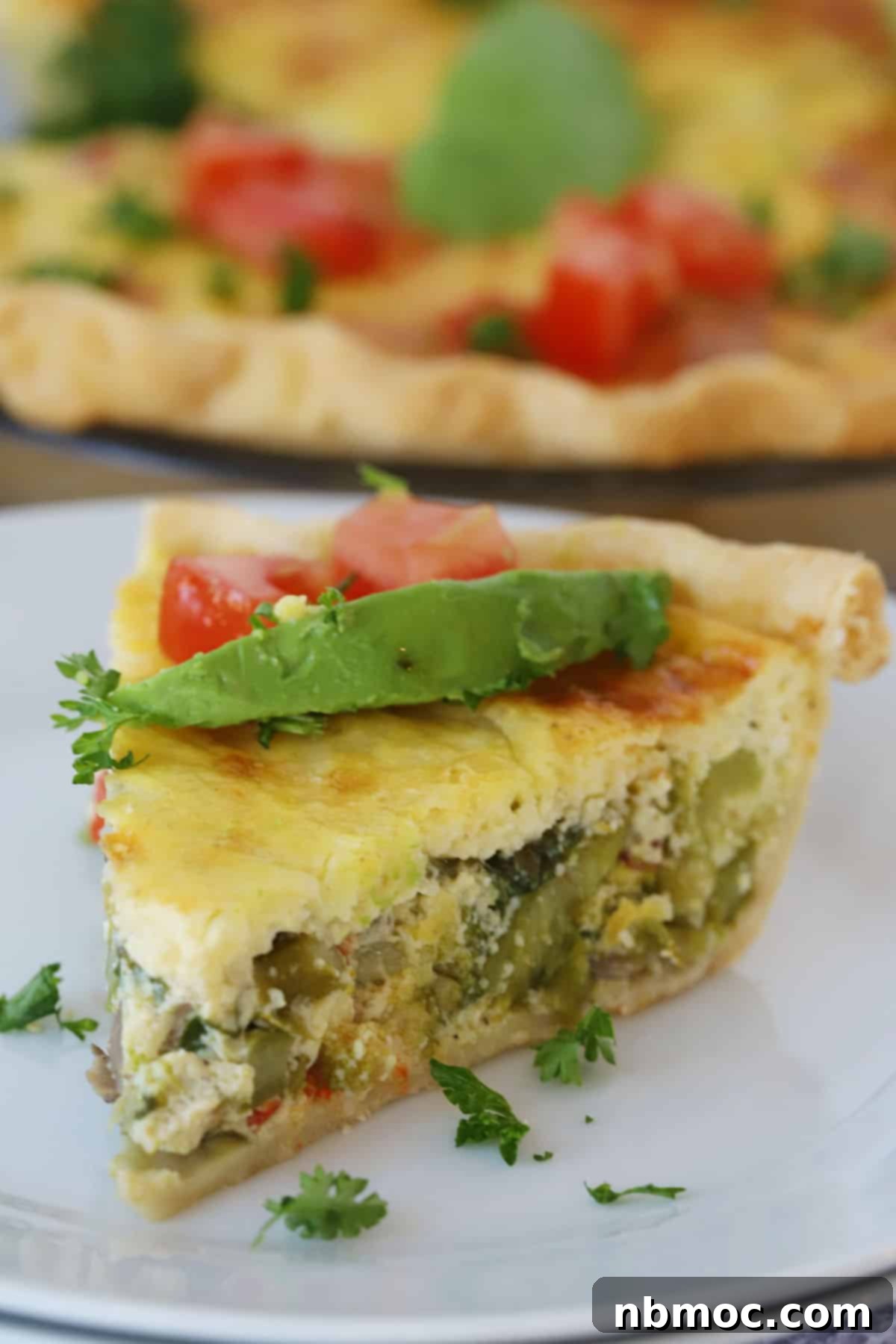 Garden Harvest Quiche 2 A slice of our vegetable quiche recipe on a white plate, topped with avocados and tomatoes.
