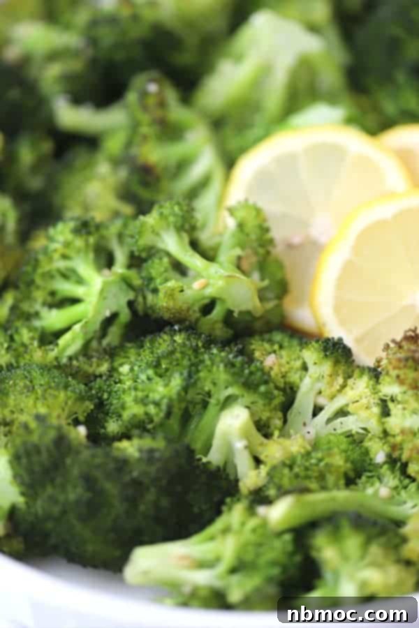 Crispy Garlic Lemon Broccoli 3 Close-up shot of garlic baked broccoli in a dish, garnished with fresh lemon slices, highlighting the golden-brown edges and vibrant green color.