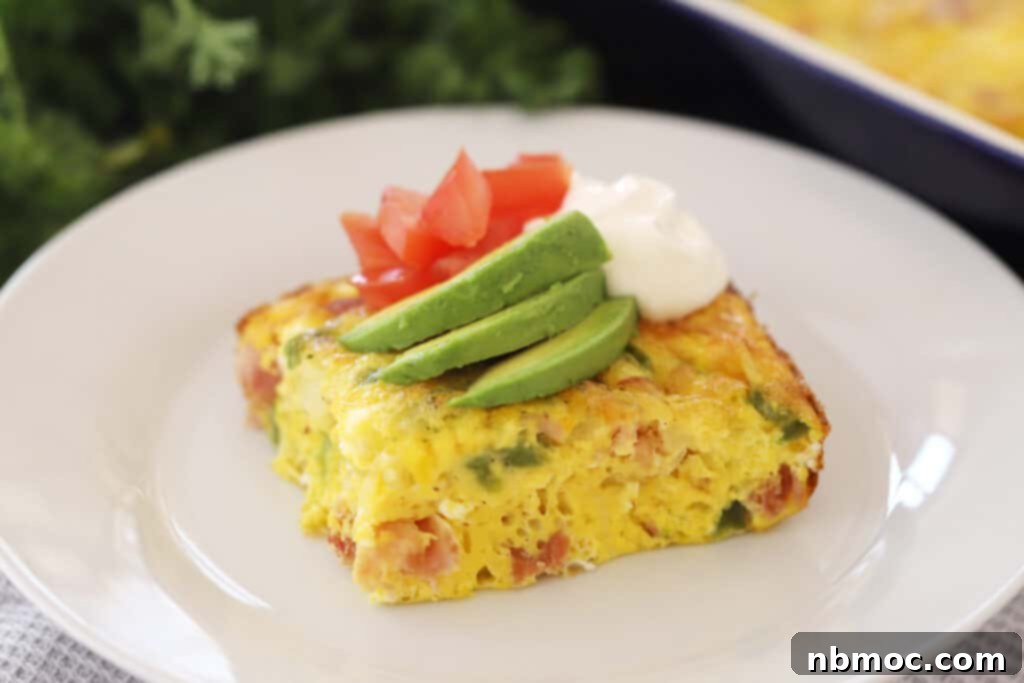 Simple Denver Omelet Breakfast Bake 6 Baked Denver omelet casserole on a white serving plate, garnished with fresh herbs.