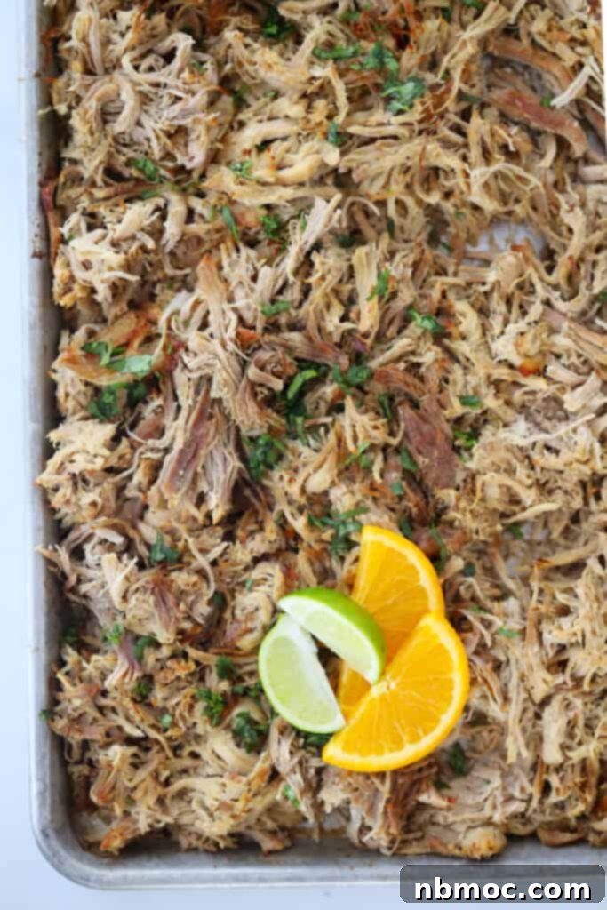 Crispy Slow Cooker Carnitas Tacos 3 A large sheet tray filled with a layer of broiled pork carnitas meat, showing crispy edges.