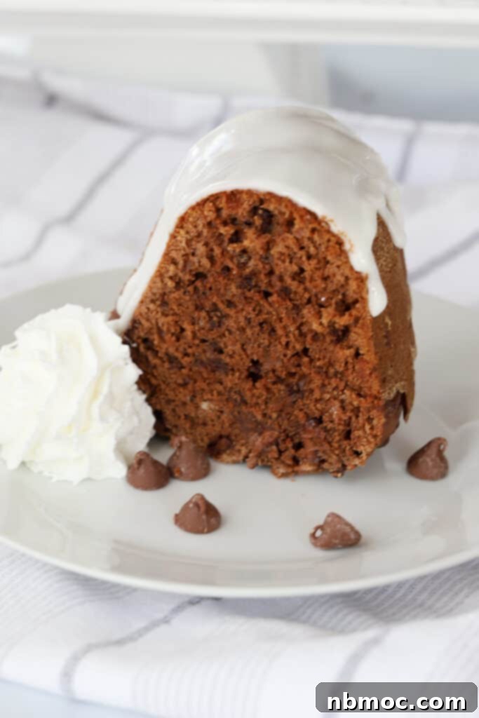 A chocolate bundt cake on a white plate topped with vanilla icing for chocolate bundt cake.