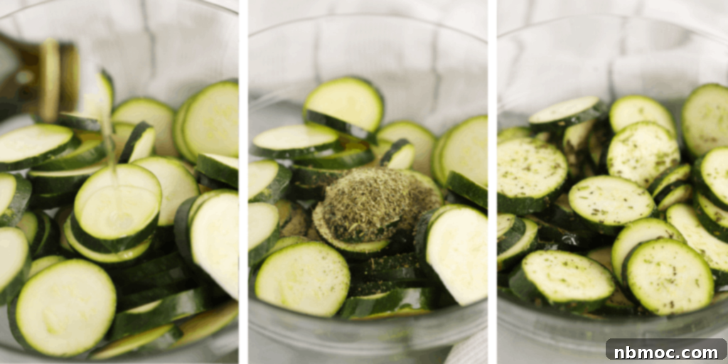 A large clear glass bowl filled with freshly sliced zucchini rounds, glistening with oil and seasonings, ready for roasting.