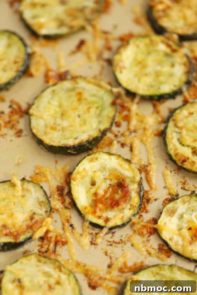 Close-up of baked Parmesan zucchini on a baking sheet, showing the rich golden-brown melted cheese and tender zucchini slices.