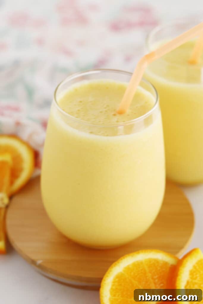 Frothy Orange Dream 2 A glass of homemade orange julius with a straw and fresh slices of oranges.