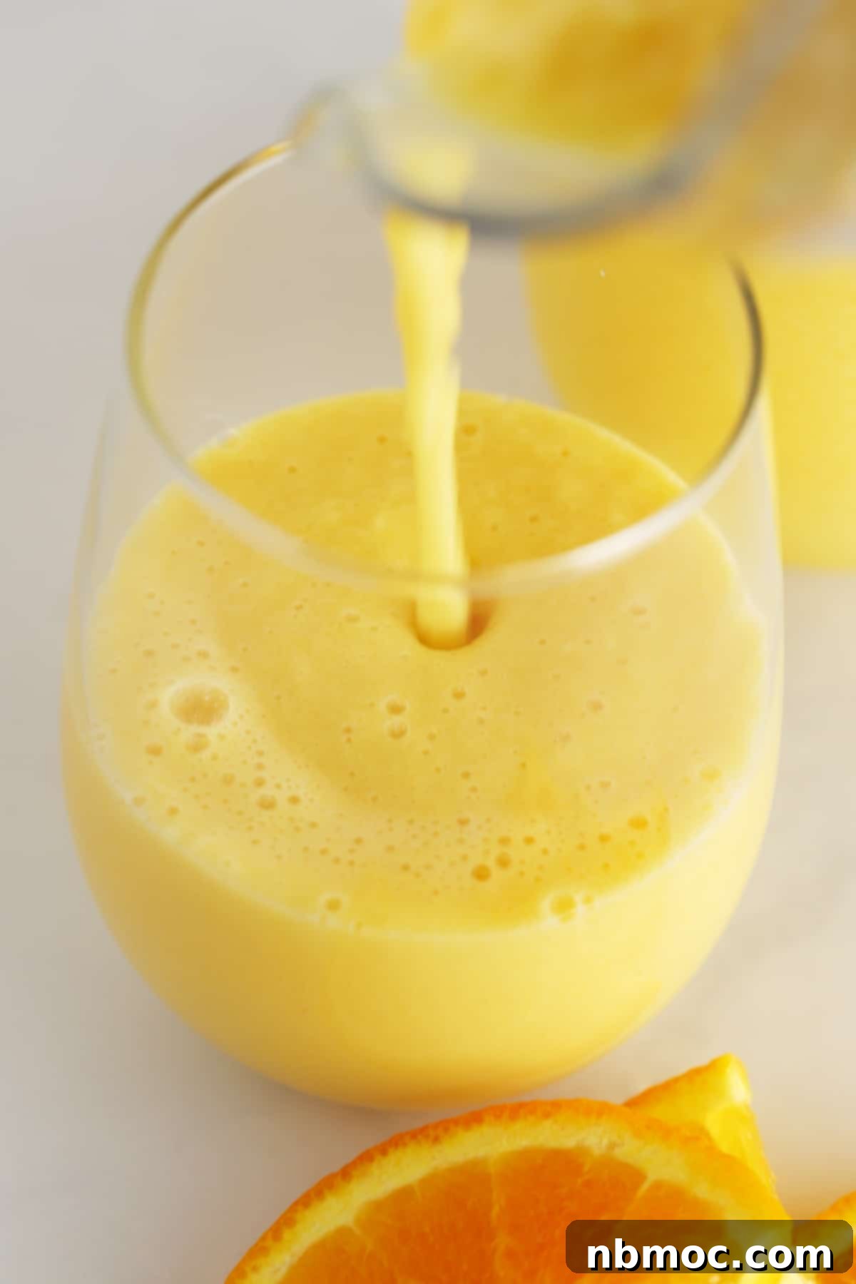 Frothy Orange Dream 3 A glass with orange julius being poured into it.