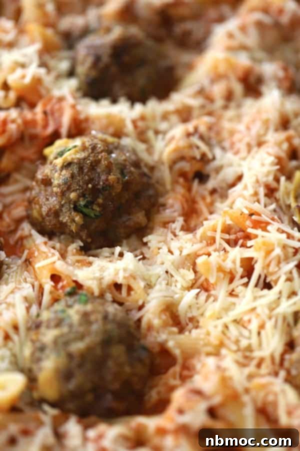 Hearty Meatball Pasta Bake 2 A delicious baked penne pasta with meatballs, bubbling hot in a baking dish, topped with golden-brown shredded mozzarella cheese, ready to be served.