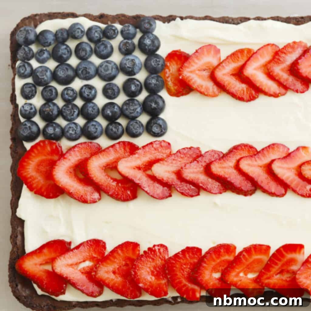 A sheet of brownies covered with cream cheese frosting and decorated with blueberries and sliced strawberries to look like the American flag. This festive dessert is perfect for 4th of July celebrations.