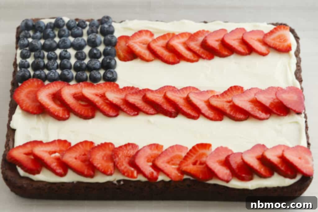 A sheet of Memorial Day Brownies (or 4th of July Brownies) decorated to look like the american flag by using cream cheese frosting and berries, ready to be cut and served.