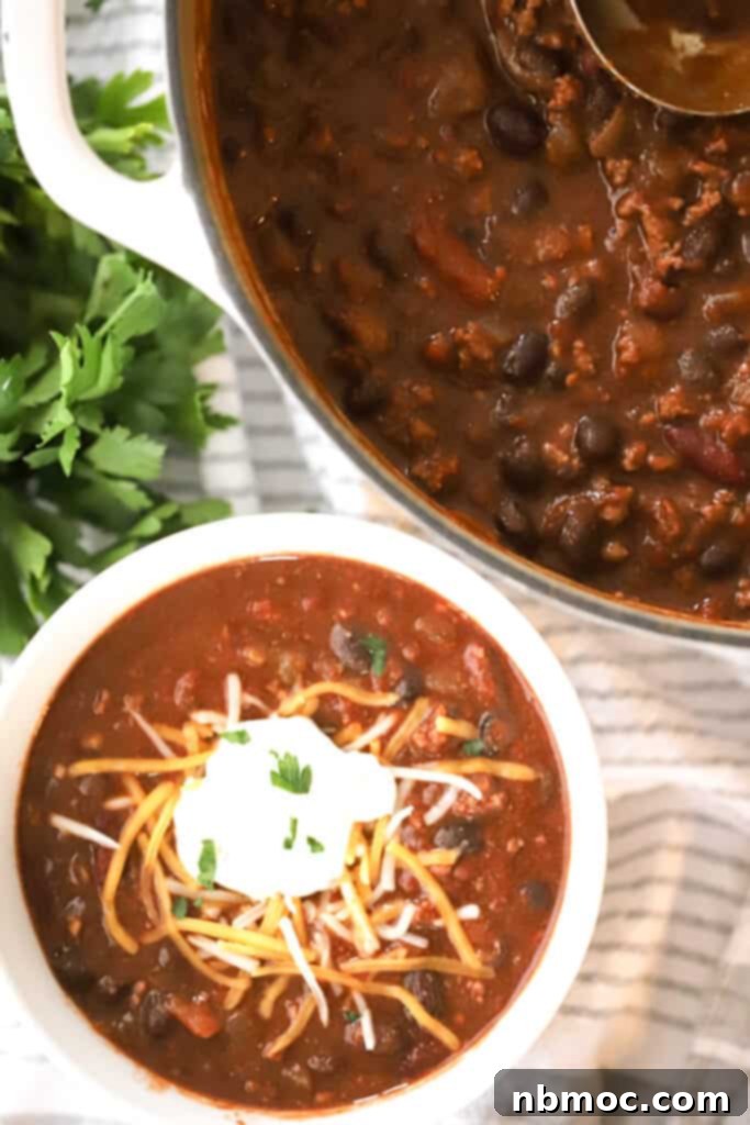 Ultimate Beef Chili 4 A serving bowl of this quick and easy beef chili, generously topped with cool sour cream and shredded cheese.