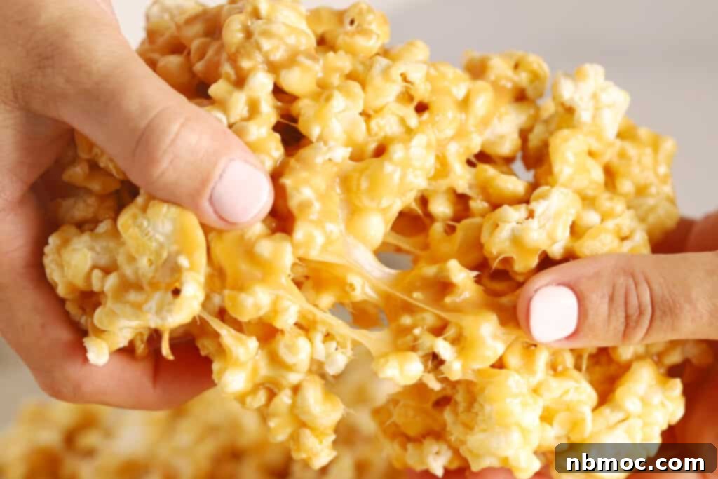 Hands pulling apart gooey caramel popcorn.