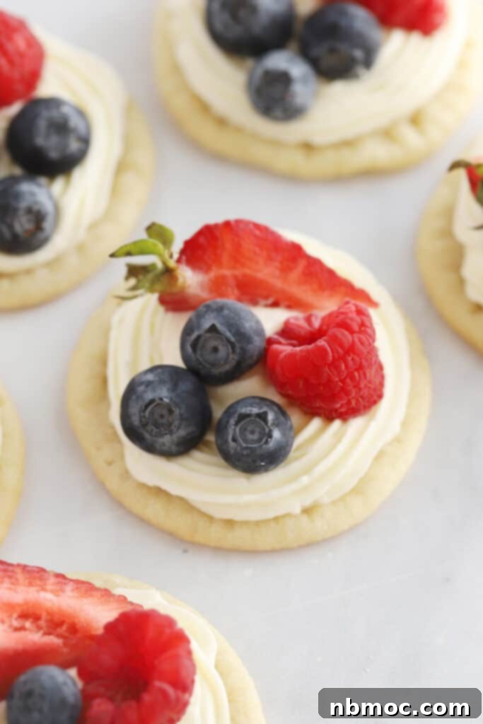 Sugar cookie fruit pizza topped with cream cheese frosting and fresh berries.