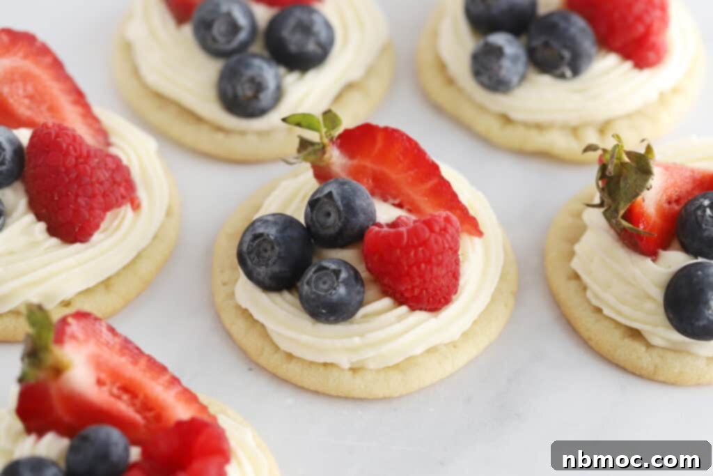 Rows of fruit pizza with cream cheese frosting and fresh fruit.